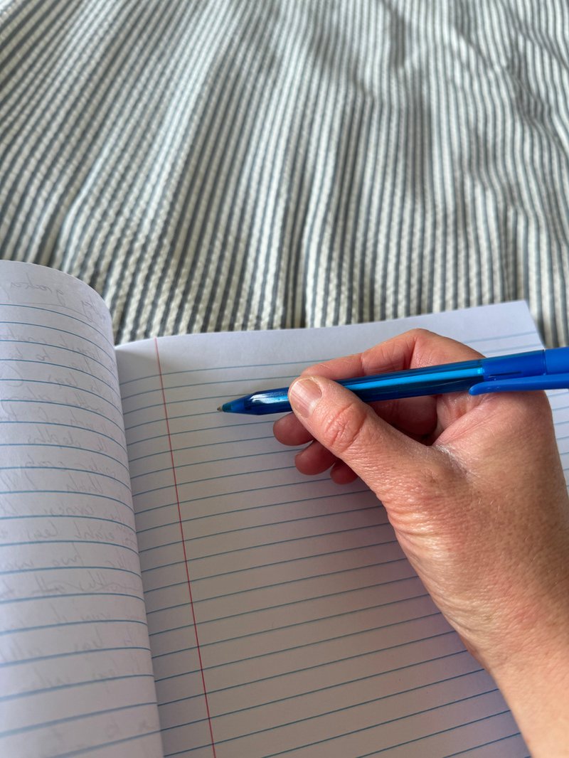 A hand writing in a lined notebook